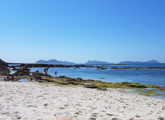 Bañistas en una playa de Vigo, con las islas Cíes al fondo